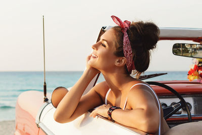 Side view of young woman sitting at beach