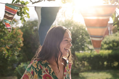 Smiling mid adult woman looking away while standing in backyard
