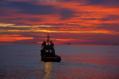 Boat sailing on sea against sky during sunset