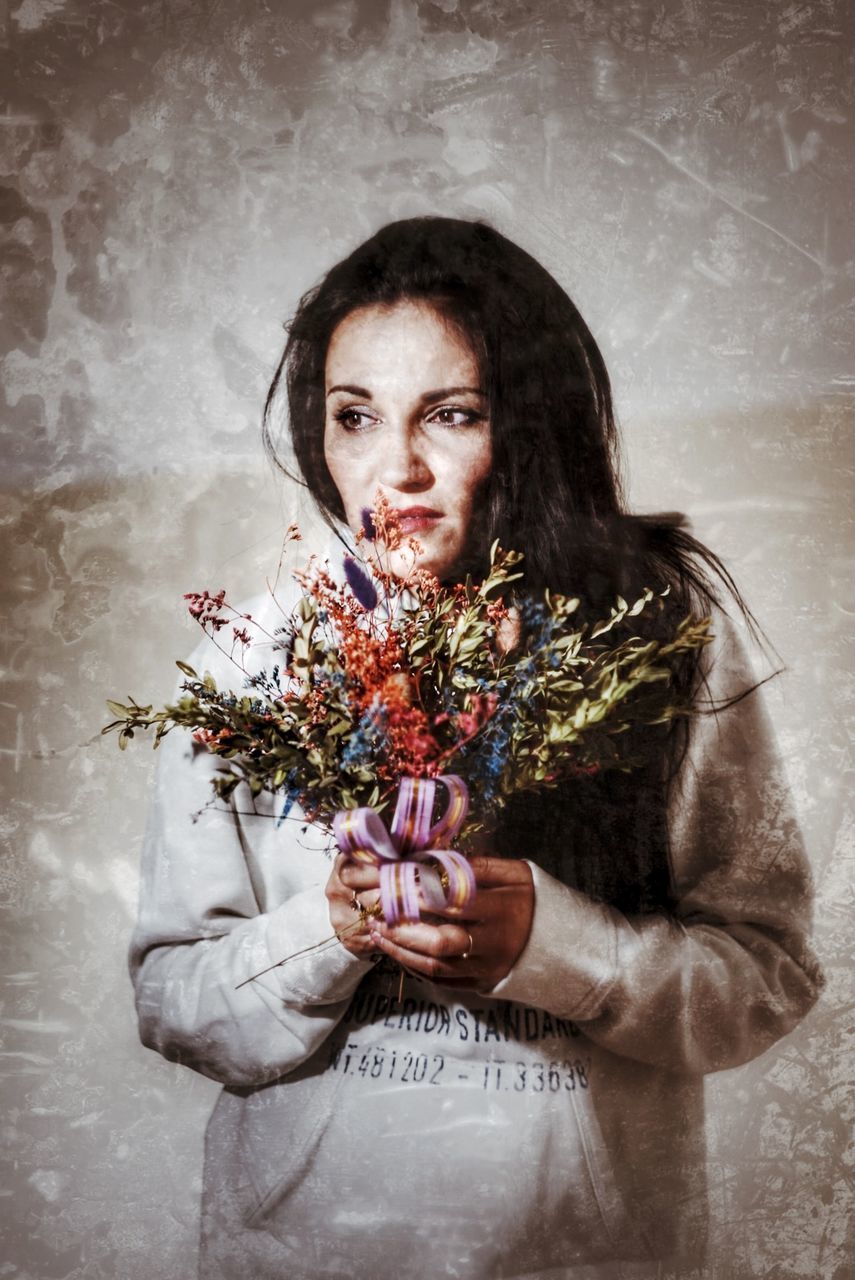 PORTRAIT OF WOMAN HOLDING FLOWER