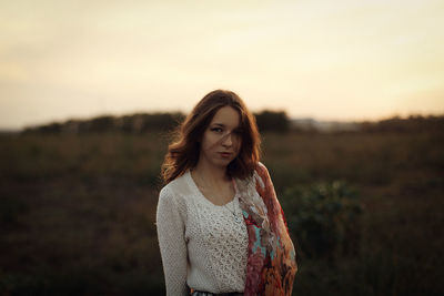 Portrait of young woman standing against sky during sunset