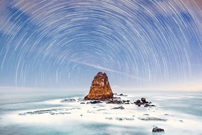 Rock formation in sea against sky