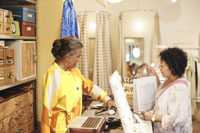 Saleswoman with disability assisting female customer doing online payment at store