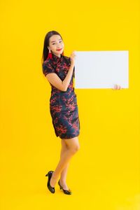 Portrait of smiling young woman against yellow background