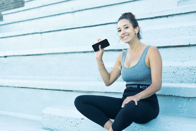 Young woman using mobile phone while sitting on table