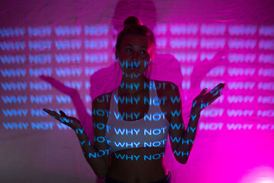 Portrait of woman standing against pink wall