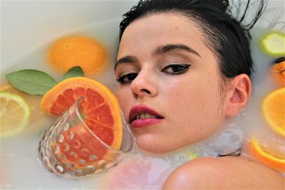 Close-up portrait of woman taking bath with fruits in bathtub