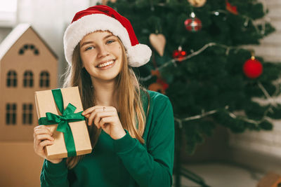 A beautiful little girl looks at the camera and smiles, holding a kraft paper gift 