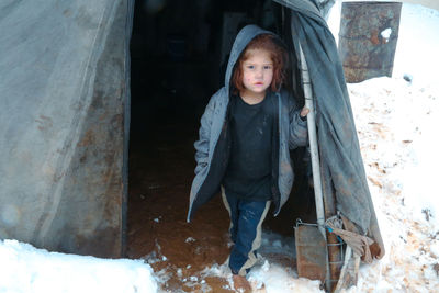 A syrian refugee child at the door of his snow covered tent