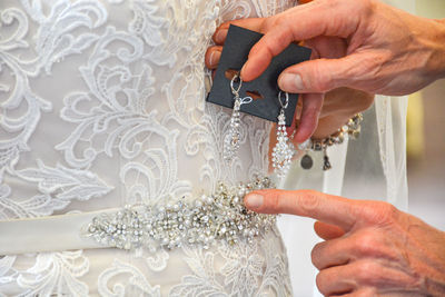 Cropped hands examining wedding dress