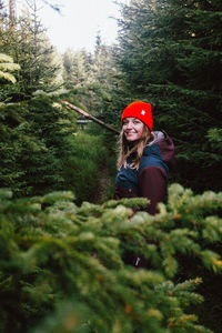 Portrait of woman standing by plants in forest
