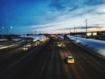 Vehicles on road against sky in city