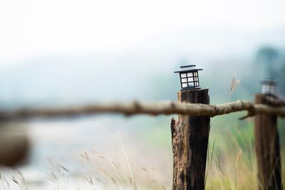 Close-up of barbed wire on wooden post against sky