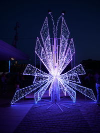 Illuminated ferris wheel against sky at night