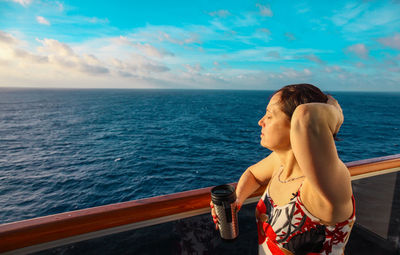 Young woman looking at sea against sky