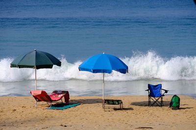 Deck chairs on beach against sky