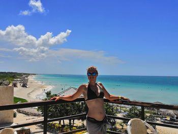 Portrait of young woman standing by sea against sky