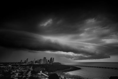 Panoramic view of sea and city against sky at dusk