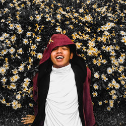 Portrait of a smiling young woman standing by flowering plants