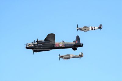 Low angle view of airplane flying against clear blue sky