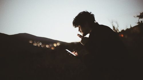 Side view of man smoking cigarette against sky