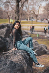 Portrait of young woman sitting on rock