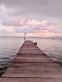 Pier over sea against sky during sunset