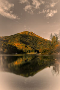 Scenic view of lake by mountain against dramatic sky