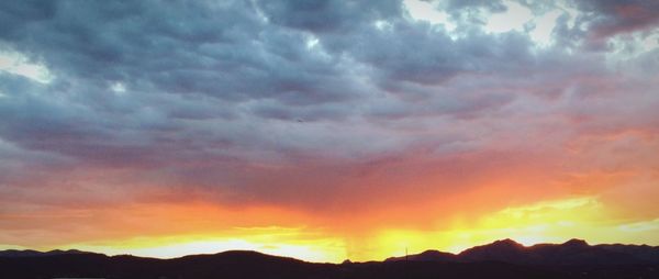 Scenic view of mountains against cloudy sky at sunset