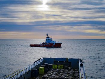 Ship sailing in sea against sky during sunset