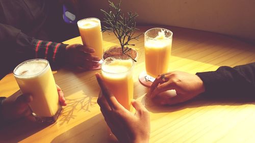 Close-up of hand holding drink on table