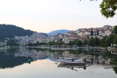 Boats moored in lake against buildings in city