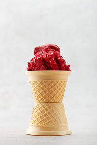 Close-up of ice cream cone on table against white background