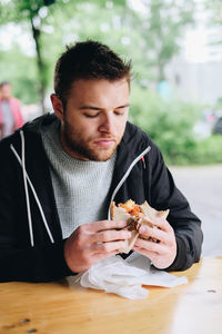 Young man eating food at restaurant table