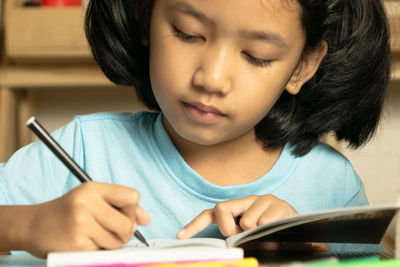 Cute girl drawing on book at home