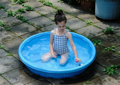 Young girl playing in the pool in the backyard