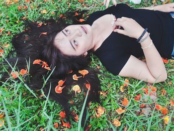 High angle view of young woman lying on grassy field during autumn