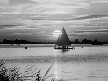 Sailboats in sea against cloudy sky during sunset