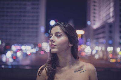 Portrait of woman looking at illuminated city at night