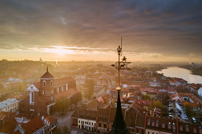 Cityscape against cloudy sky during sunset