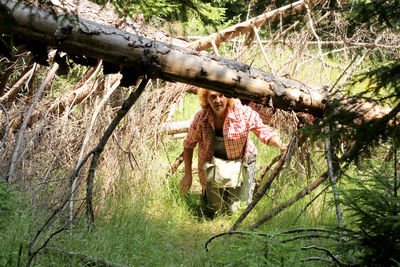 Woman standing by tree trunk in forest