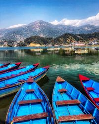 Boats moored in lake against blue sky