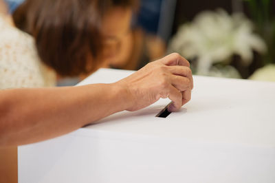 Cropped hand of woman casting vote in ballot box