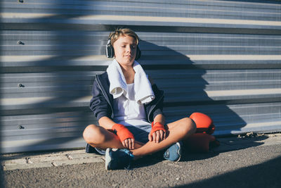 Portrait of boy sitting on floor in city