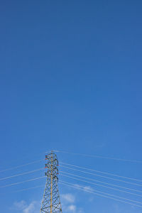 Low angle view of electricity pylon against blue sky