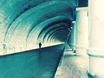 Rear view of man walking in tunnel