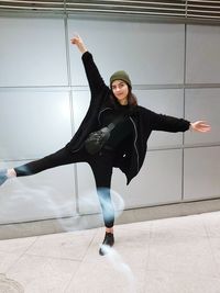 Portrait of young woman with arms outstretched standing on floor