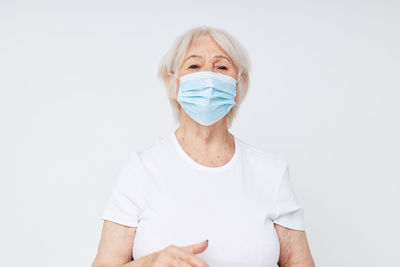 Portrait of senior woman wearing mask against white background