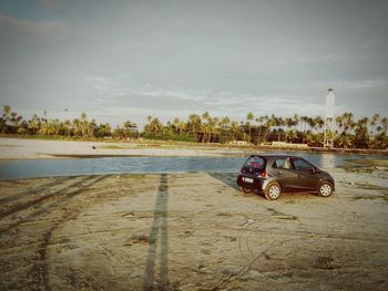 Car on sand against sky