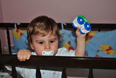 Baby boy sucking pacifier in crib at home